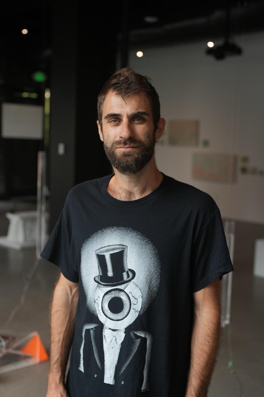 A man displays a t-shirt adorned with a graphic of a man in a top hat, showcasing a casual yet stylish look.