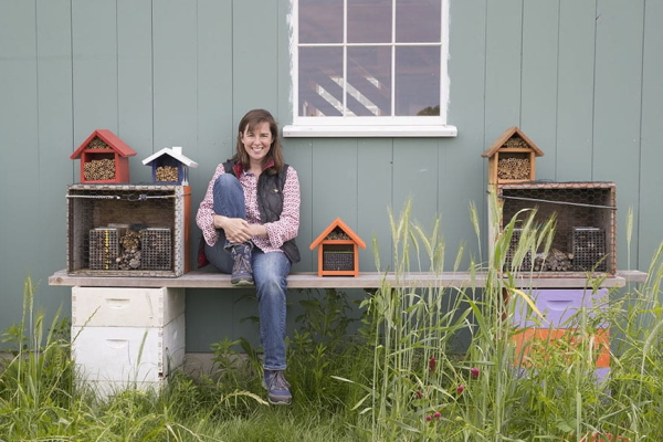 Bee rancher Laura Klahre sits by her mason bee cottages at Blossom Meadow Farm in Southold. 