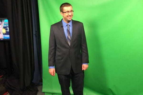 Michael Colbert stands in front of a green screen